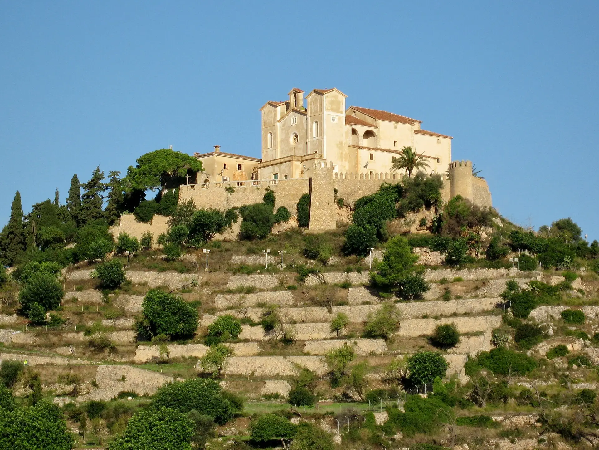 The sanctuary of Sant Salvador above the terraced walls of Artà in evening light