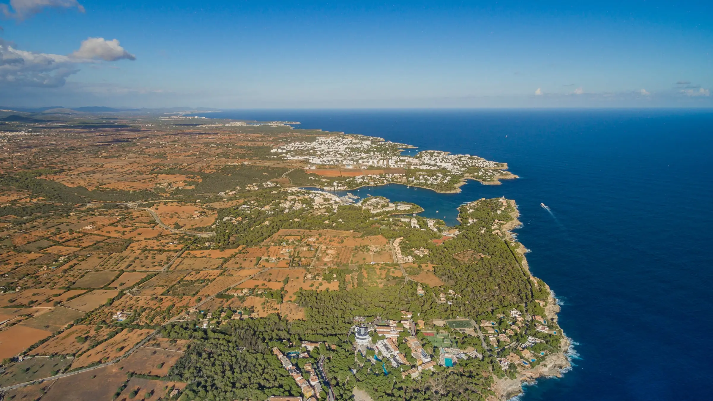 Aerial view of the Cala d'Or coastline with its white low-rise town and the marina in Cala Llonga
