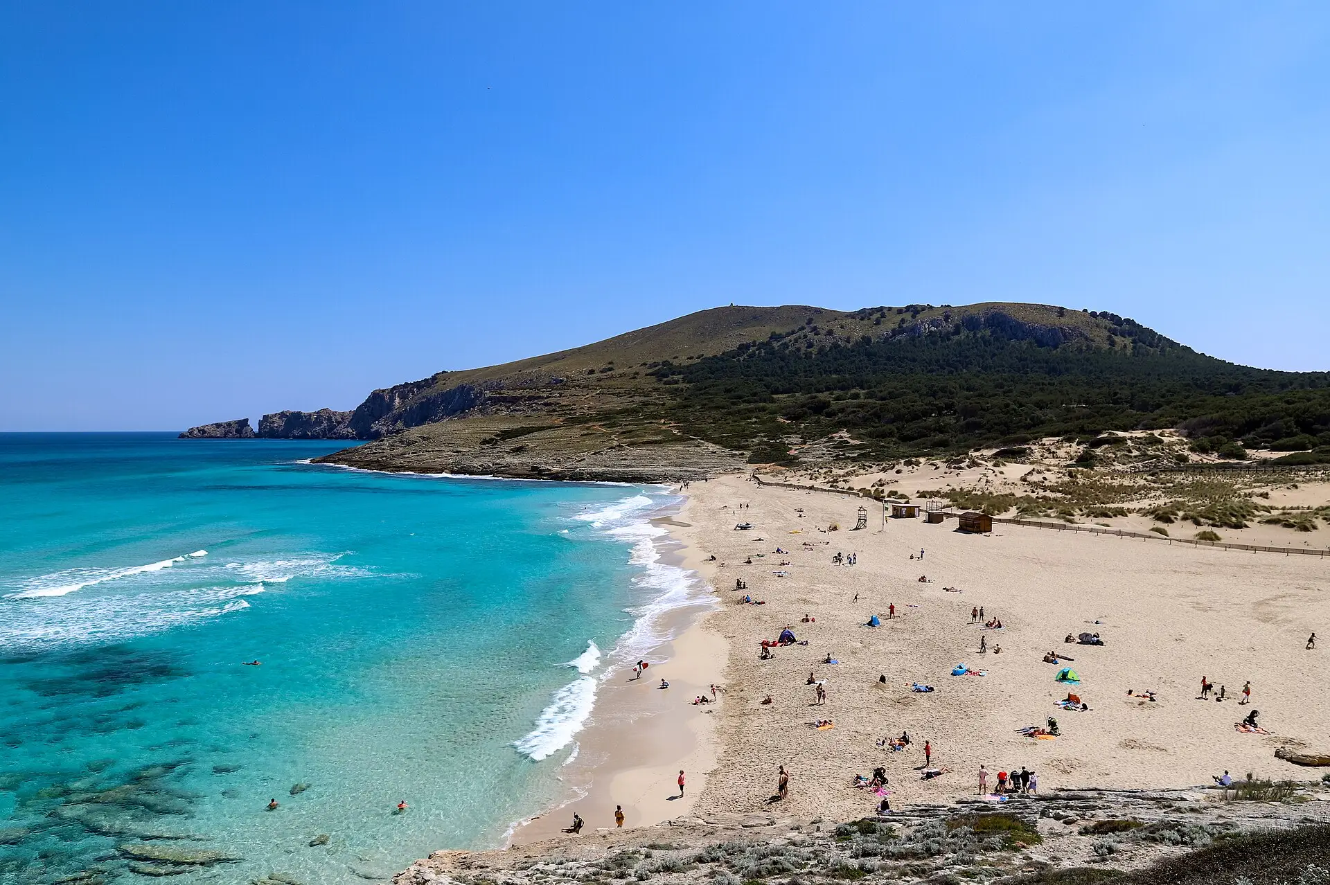 The wide bay of Cala Mesquida with turquoise water and protected dunes, the Talaia de Son Jaumell behind