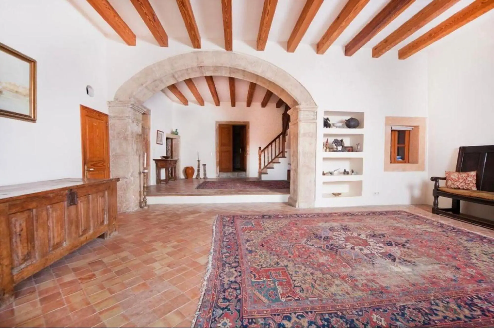 Entrance hall with stone arch, terracotta floor and open staircase