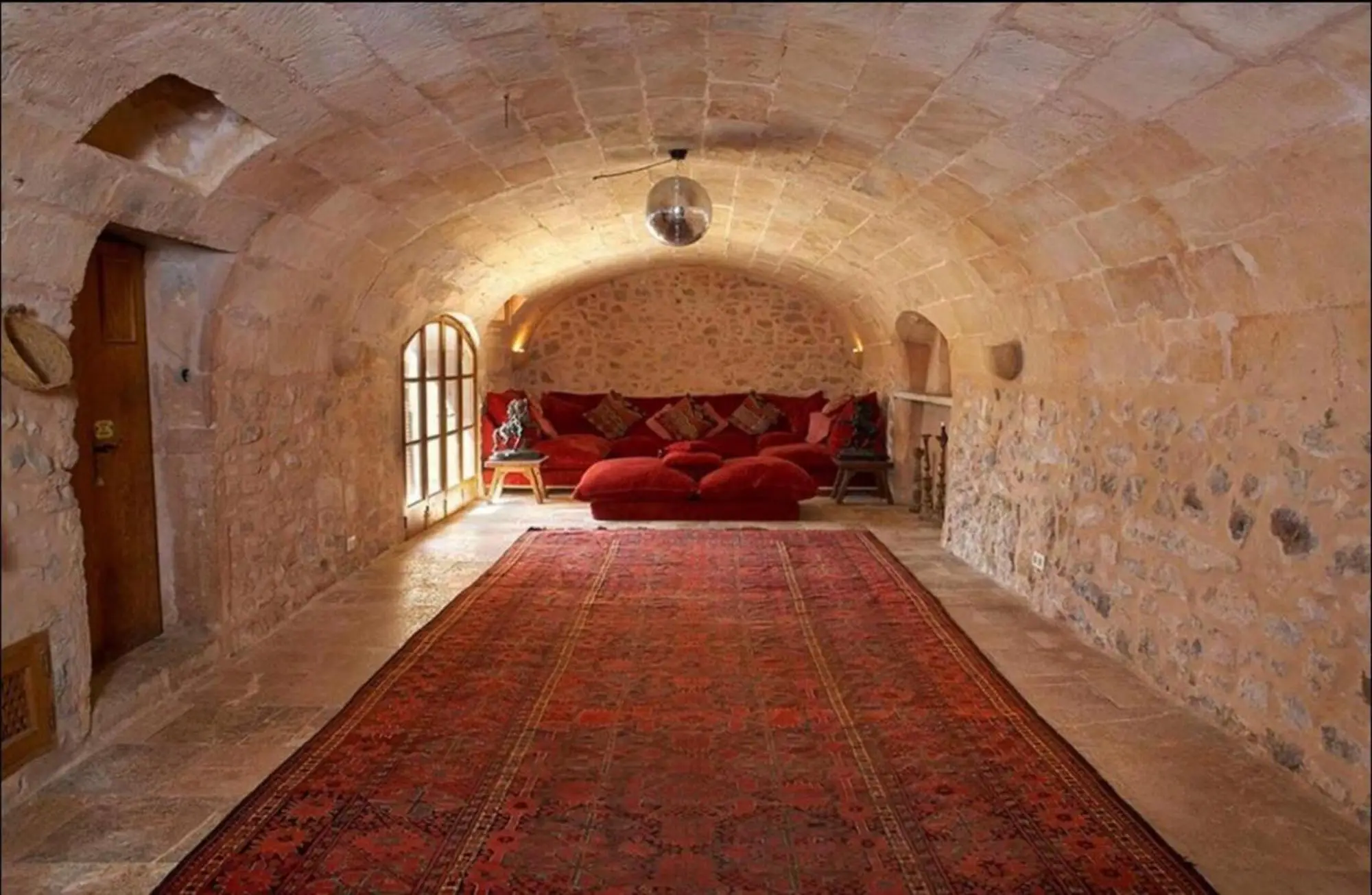 Vaulted hall of hand-cut stone, furnished as a lounge with a rug