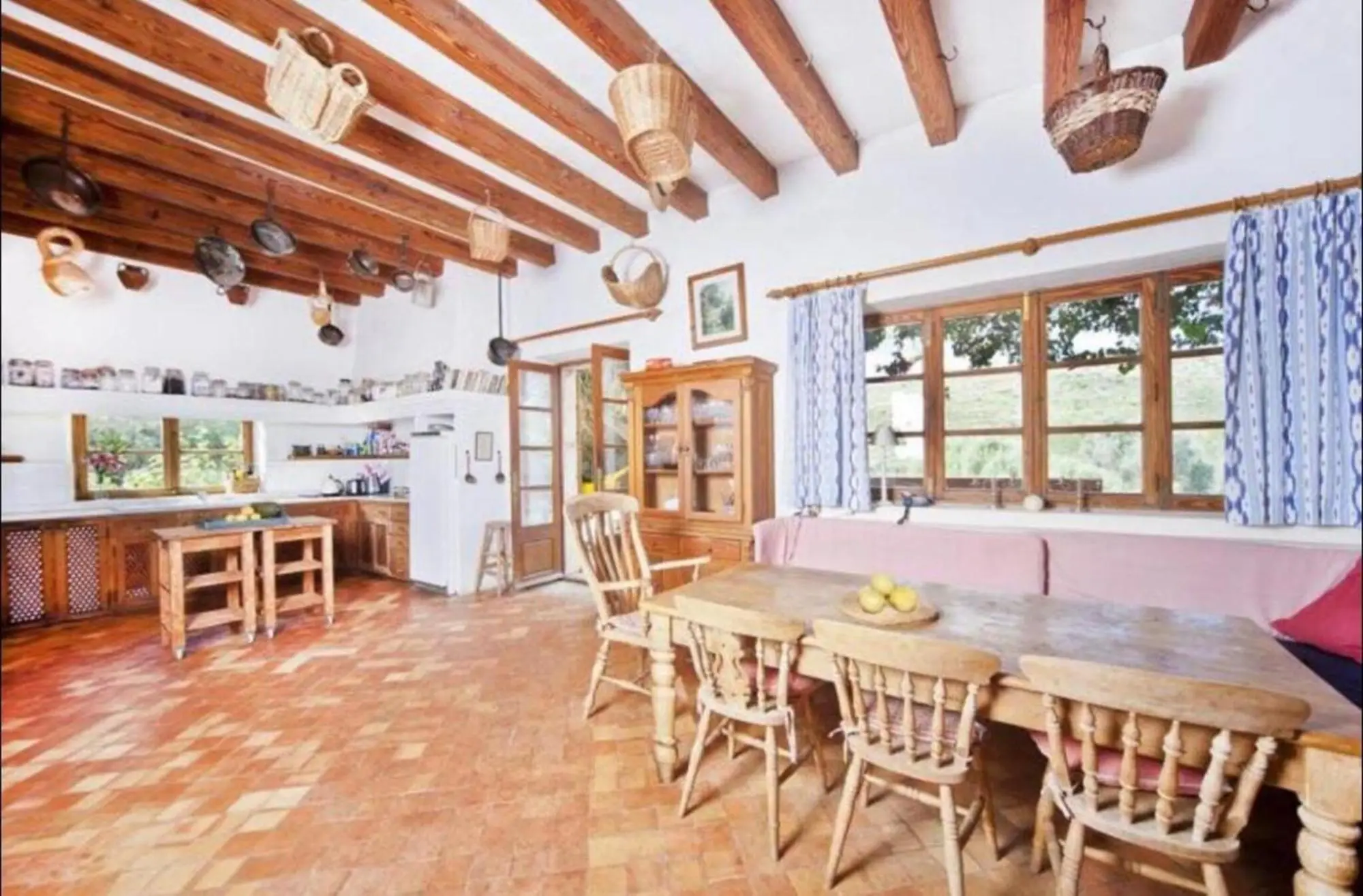 Country kitchen with a long dining table, terracotta floor and beamed ceiling