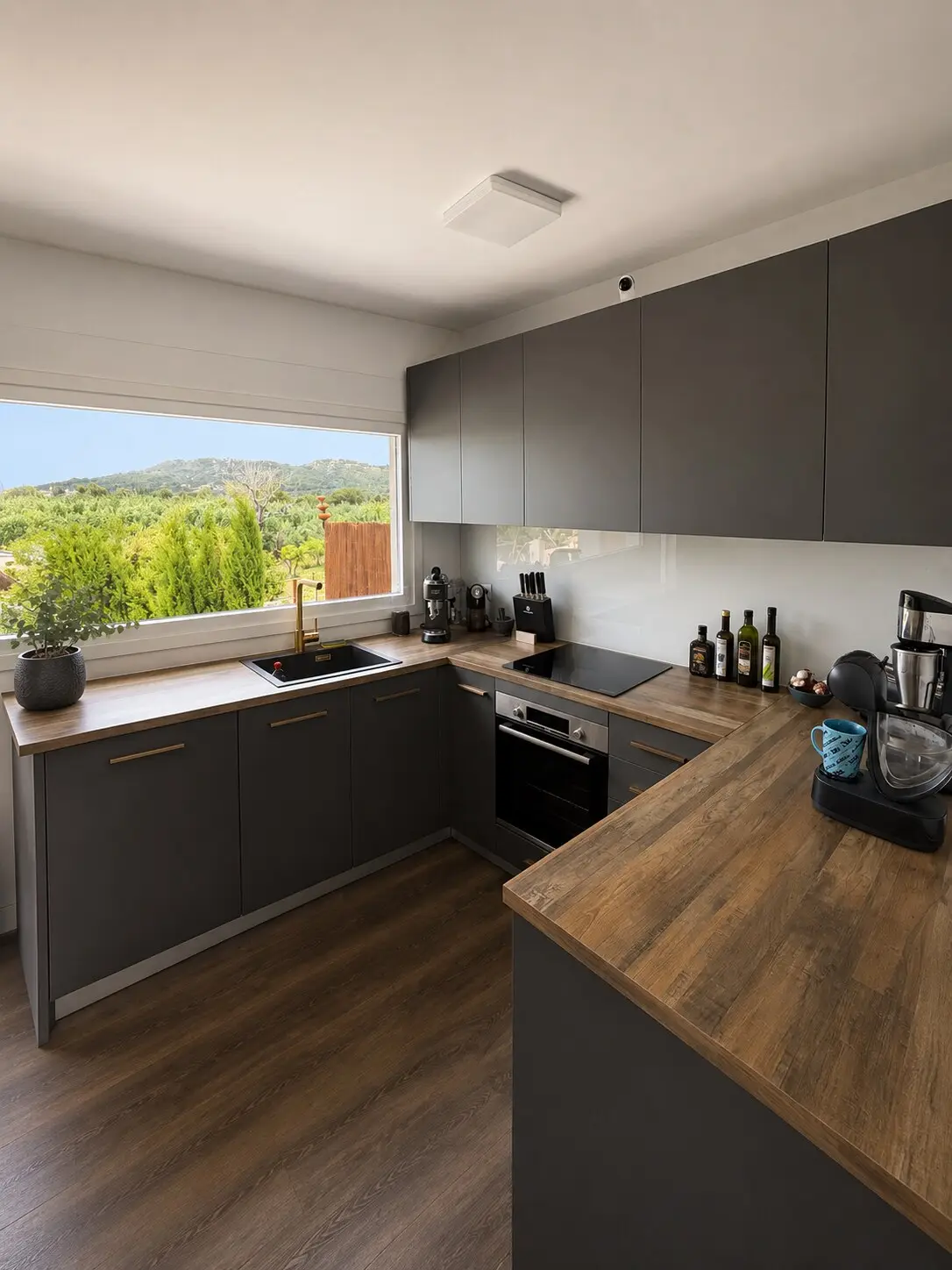 Kitchen with grey fronts, wooden worktop and a window onto the greenery