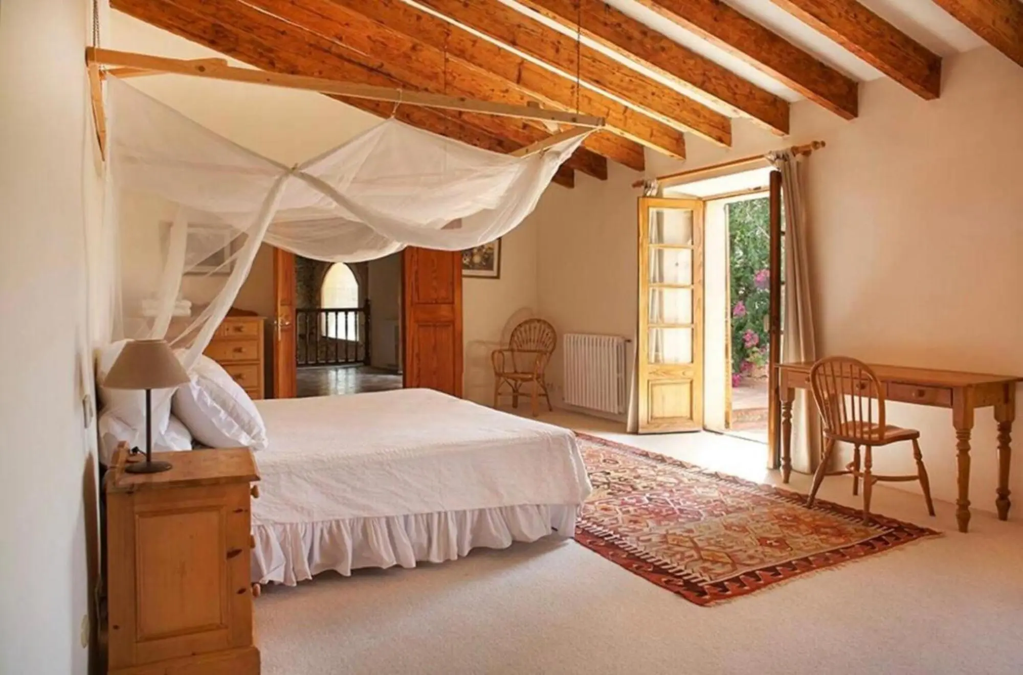 Bedroom with four-poster bed, beamed ceiling and French doors