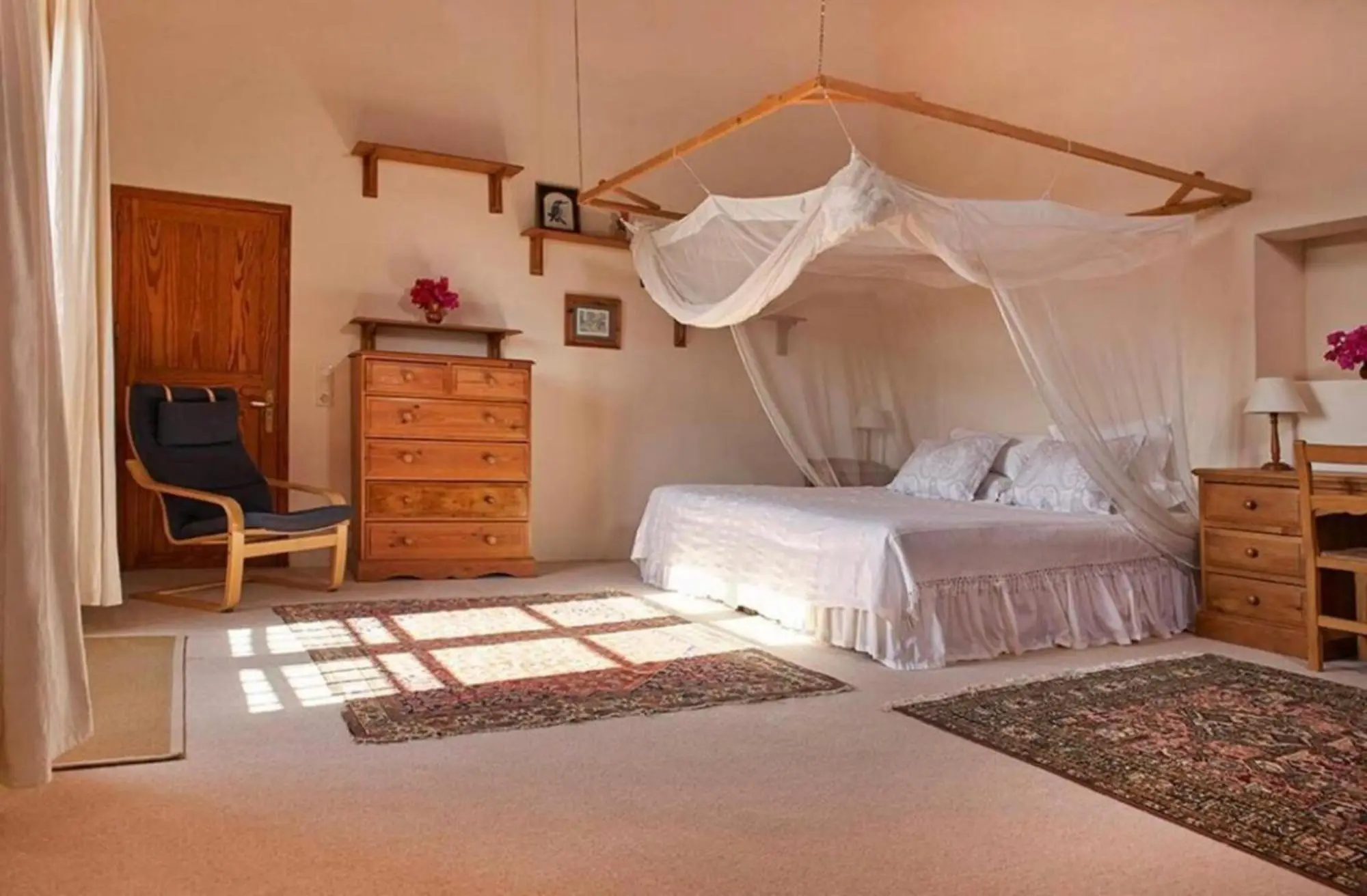 Bedroom with four-poster bed, wooden chest of drawers and armchair