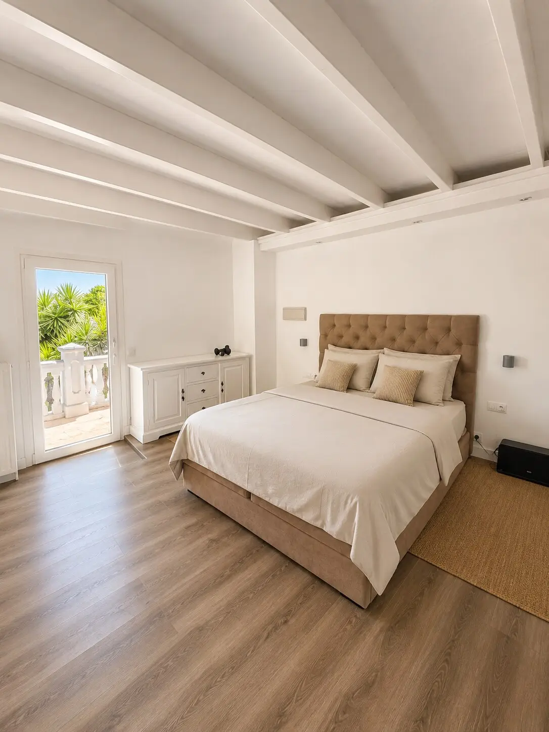 Bedroom with upholstered headboard, wooden floor and exposed beams