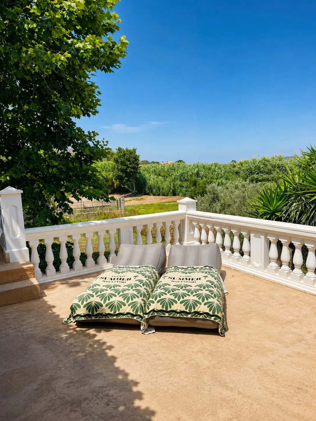 Terrace with cushions on the balustrade, looking over trees and fields