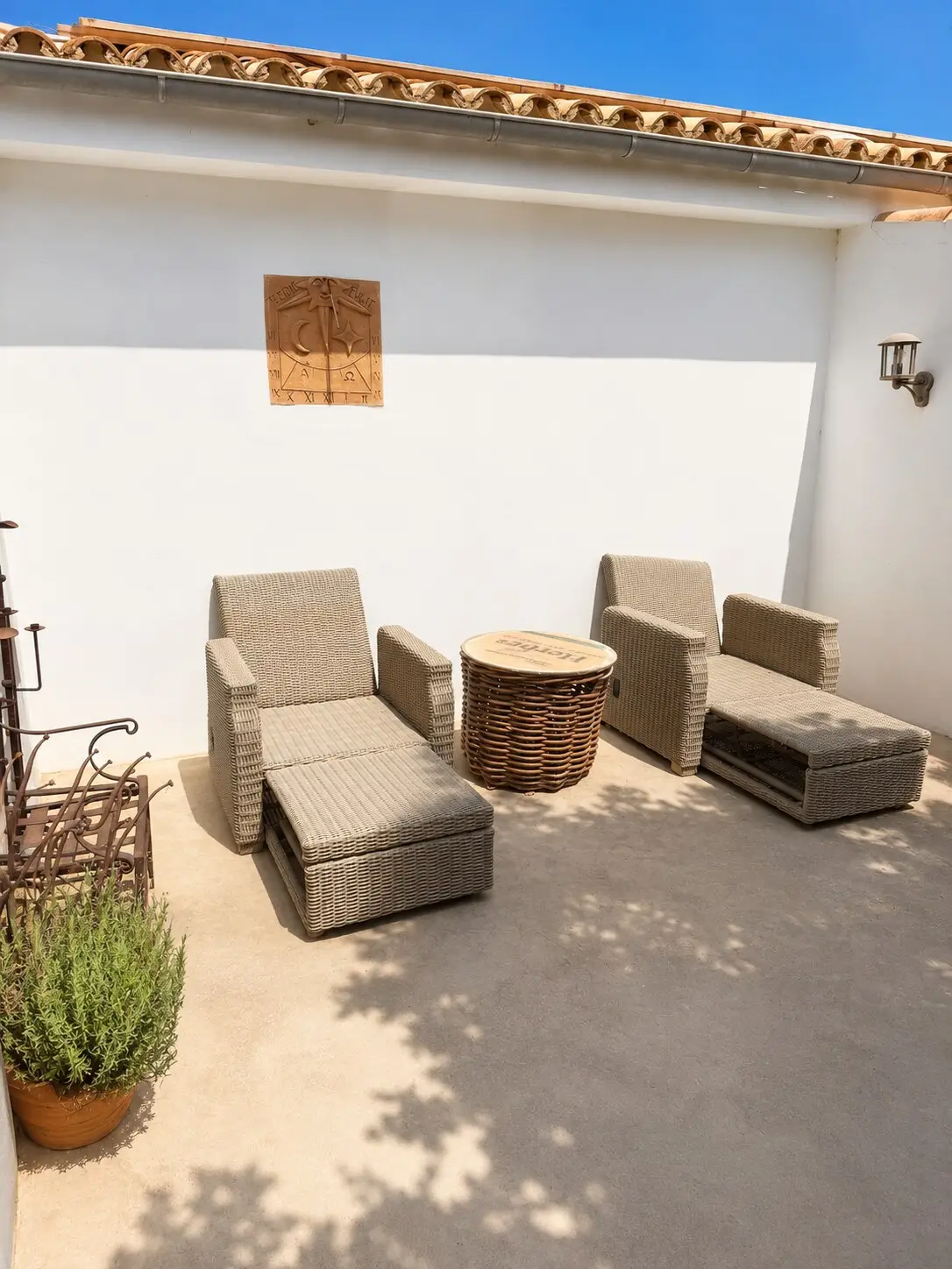 Rattan sun loungers on the terrace against the white house wall